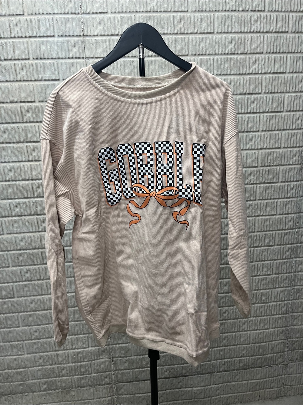 Beige Graphic Sweatshirt with Checkerboard Lettering and Orange Bow